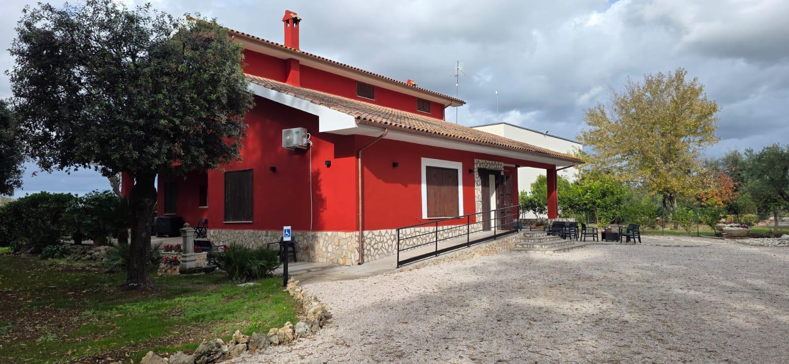 Villa rossa di Casa Alloggio La Roccia immersa nel verde a Latina